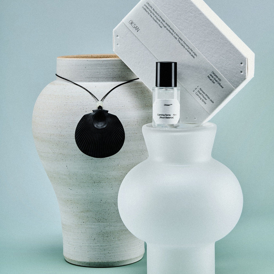 The Oksan Jade Shell Diffuser Ritual Set styled with a Korean white moon jar and a frosted glass vessel on a cool grey backdrop
