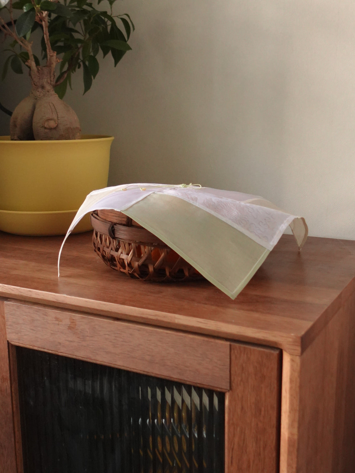 Jogakbo Silk Table Cover in Jade, draped over a basket on a wooden console — celadon panel visible
