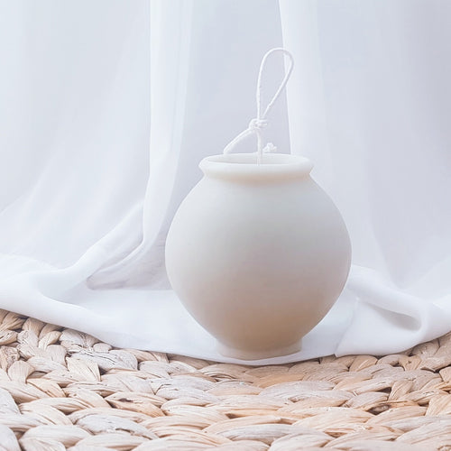 Moonlight White moon jar candle on a woven mat by a linen curtain