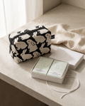 The Washbag Set — Little Black Bunnies box pouch beside an open Oksan jade perfume soap duo on a pale stone counter